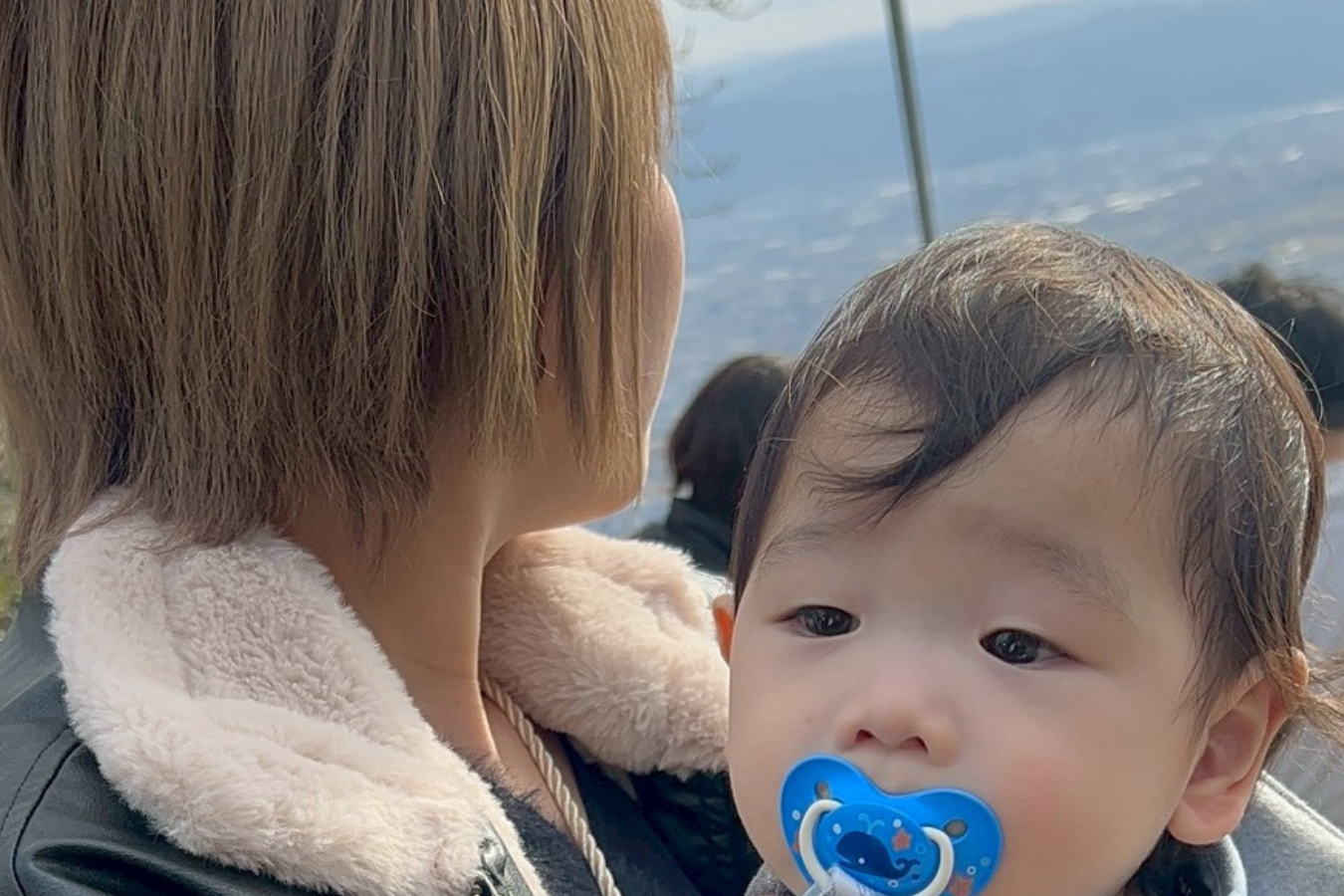 息子を抱きながら外の景色を見つめる山口美生さん。シングルマザーとしての不安や葛藤を抱えながらも、未経験からウェブマーケターへキャリアチェンジし、自分らしい働き方と人生を築いてきた。子育てを理由に何かを諦めるのではなく、「好きな自分で生きる」という価値観を体現する一枚。